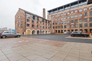 two cars parked in a parking lot in front of buildings at Lovely Riverside 2 Bed Apartment in Leeds