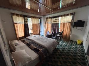 a bedroom with a bed and a desk and windows at Forest inn in Pahalgām