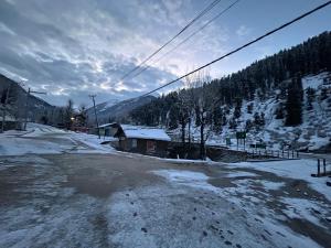 a snow covered road with a building and a mountain at Forest inn in Pahalgām