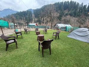 a group of chairs sitting in the grass at Forest inn in Pahalgām