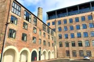 a large brick building with a car parked next to it at Spacious 1 Bedroom Apartment in a Converted Mill in Leeds