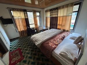 ein Schlafzimmer mit einem Bett in einem Zimmer mit Fenstern in der Unterkunft Forest inn in Pahalgām