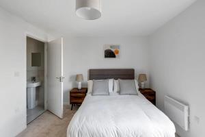 a white bedroom with a large bed and a sink at Spacious 1 Bedroom Apartment in a Converted Mill in Leeds