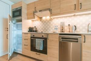 a kitchen with wooden cabinets and stainless steel appliances at Cozy Chic Studio with Balcony The Greens Dubai in Dubai