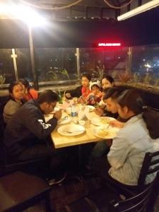 Eine Gruppe von Menschen, die an einem Tisch sitzen und Essen essen. in der Unterkunft HOTEL GRAND PALACE & BANQUET in Shiliguri