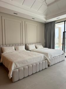 a large white bedroom with two large beds at Alreef farm in Ras al Khaimah