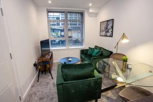 a living room with a glass table and green chairs at Cosy 1 Bedroom Apartment in Bolton in Bolton