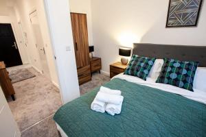 a bedroom with a green bed with towels on it at Cosy 1 Bedroom Apartment in Bolton in Bolton