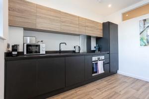 a kitchen with black cabinets and a microwave at Modern 2 Bedroom Apartment in Bolton in Bolton +7 photos