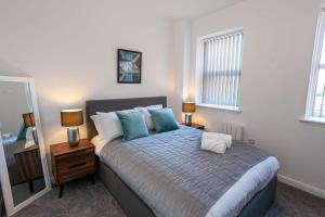 ein Schlafzimmer mit einem Bett mit zwei Lampen und einem Spiegel in der Unterkunft Modern 2 Bedroom Apartment in Bolton in Bolton