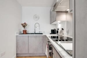 a white kitchen with a sink and a counter at Beautiful 2 Bed Apartment in a Converted Mill in Leeds