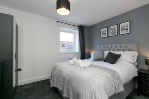 a bedroom with a bed with white sheets and a window at Stunning 2 Bedroom Apartment in Wallasey in Wallasey