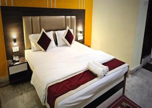 een slaapkamer met een groot bed met witte lakens en kussens bij STAYMAKER The Altira in Jamshedpur