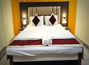 a bedroom with a large bed with slippers on it at STAYMAKER The Altira in Jamshedpur