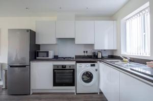 uma cozinha com armários brancos e uma máquina de lavar roupa em Lovely brand new 3 bedroom city centre house with garden em Derby