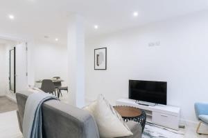 a white living room with a couch and a tv at Centrally Located 1 Bedroom Apartment in Ipswich in Ipswich