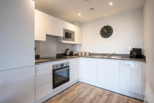 uma cozinha com armários brancos e um relógio na parede em Stylish and Comfortable 1 Bedroom Apartment in Birmingham em Birmingham