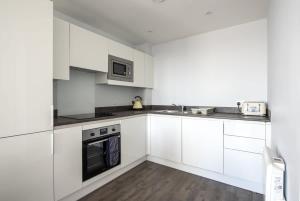 a white kitchen with white cabinets and appliances at Superb 2 Bedroom Aparttment in Central Birmingham in Birmingham