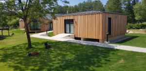 a wooden building with a dog sitting in the grass at Waidlerland Waldkirchen Chalets in Waldkirchen