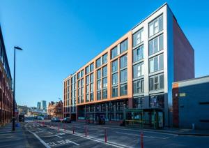 a large building on a city street with a bus stop at Superb 2 Bedroom Aparttment in Central Birmingham in Birmingham