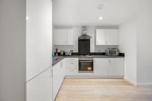 a white kitchen with white cabinets and a wooden floor at A Lovely 2 Bedroom Apartment in the Heart of Preston in Preston