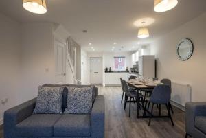 een woonkamer met een bank en een tafel met stoelen bij Modern 3 Bedroom House in Central Derby in Derby