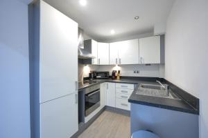 a kitchen with white cabinets and a sink at Lovely 2 Bedroom Apartment in Preston in Preston