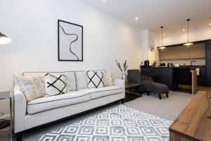 a living room with a white couch and a kitchen at Contemporary Bolton Apartment in Central Location in Bolton