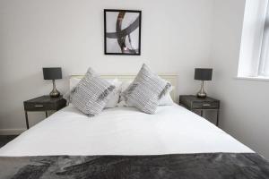 1 dormitorio con 1 cama blanca y 2 mesitas de noche en Contemporary Bolton Apartment in Central Location en Bolton