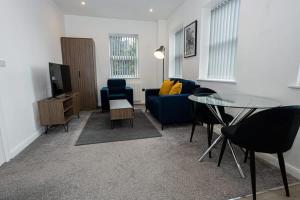 a living room with a blue couch and a glass table at Modern 1BR Bolton Apartment in Central Location in Bolton