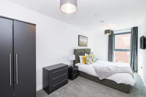 a bedroom with a bed with a black dresser and a window at Stylish 2 Bedroom Apartment by Old Trafford in Manchester