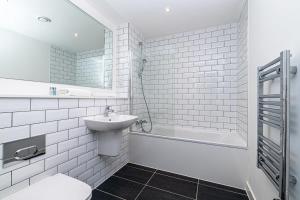 a bathroom with a sink and a toilet and a tub at Stylish 2 Bedroom Apartment by Old Trafford in Manchester