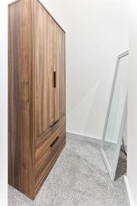 a wooden cabinet in a room next to a mirror at Contemporary 1 Bedroom Apartment in Dudley in Brierley Hill