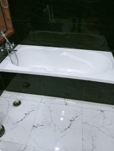 baño con bañera blanca y suelo de mármol. en wooden suits, en Ghaziabad
