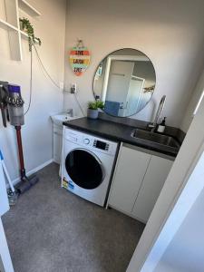eine Waschküche mit einem Waschbecken und einer Waschmaschine in der Unterkunft Ultimate Family Holiday - Pet Friendly! in Papamoa