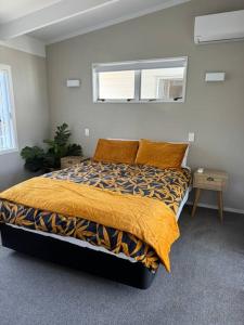 ein Schlafzimmer mit einem Bett mit einer gelben Decke und einem Fenster in der Unterkunft Ultimate Family Holiday - Pet Friendly! in Papamoa