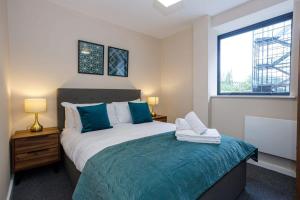 - une chambre avec un lit doté d'oreillers bleus et d'une fenêtre dans l'établissement Modern 1 Bedroom Apartment, Manchester, à Manchester