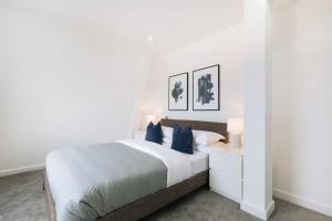 a white bedroom with a bed with blue pillows at Modern 1BR Top Floor Apartment in Ipswich in Ipswich