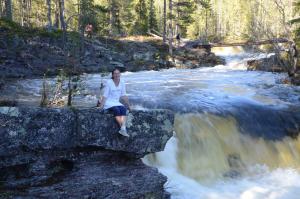 a woman sitting on a rock next to a river at 16-Nasjonalpark, sykling, fisking, kanopadling, skogs- og fjellturer in Ljørdal