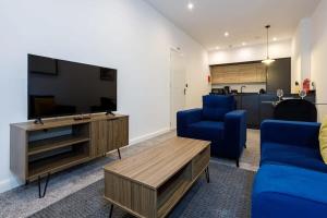 uma sala de estar com uma televisão de ecrã plano e cadeiras azuis em Contemporary 1 Bed Apartment Central Bolton em Bolton