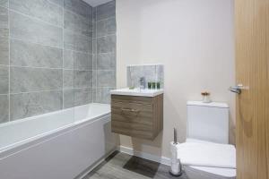 a bathroom with a tub and a toilet and a sink at Modern 2 Bedroom Apartment Manchester in Manchester