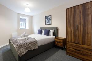 a bedroom with a bed and a wooden cabinet at Modern 2 Bedroom Apartment Manchester in Manchester