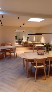 una habitación grande con mesas y bancos y una habitación con mesas en The Bakery en De Haan
