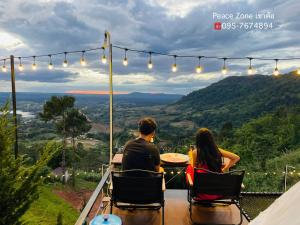 una pareja sentada en una mesa con vistas a las montañas en Peace Zone เขาค้อ, en Khao Kho