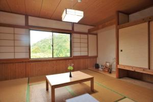 Cette chambre comprend une table et une fenêtre. dans l'établissement 山荘梶ヶ森, à Ōtakuchi
