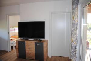 een woonkamer met een flatscreen-tv op een houten kast bij Hiška Mirna ravnica in Moravske-Toplice