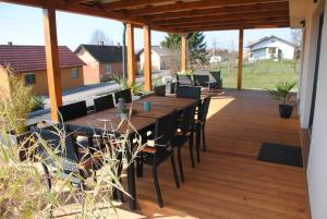 a wooden deck with a long table and chairs at Hiška Mirna ravnica in Moravske-Toplice
