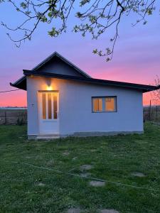 uma pequena casa branca com um pôr-do-sol ao fundo em Salaš na dan, Futog em Futog