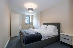 een slaapkamer met een bed met witte lakens en een nachtkastje bij Fantastic Modern 2 Bedroom Apartment, Manchester in Manchester