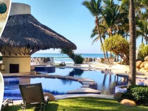 ein Resortpool mit Palmen und dem Meer in der Unterkunft Vidamar Refugio Costero / Zona Diamante in Acapulco